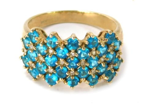 A 9ct gold dress ring, the central panelled design set with vivid blue semi precious stones, and intertwined with CZ stones , ring size P, 3.9g all in.