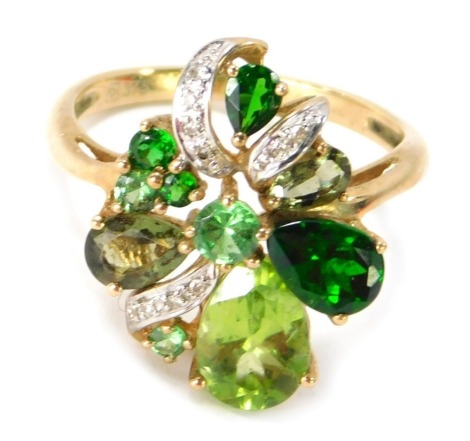 A 9ct gold peridot and green stone set dress ring, the scroll design with three leaf clover, peridot and emerald, set with CZ breaks, on a raised basket, ring size P½, 3.6g all in.