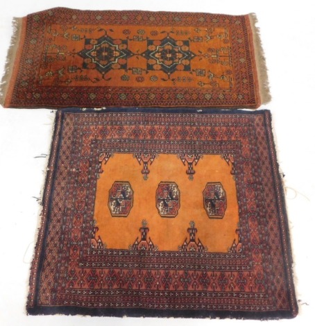 Two Afghan or Pakistani burnt orange rugs, comprising two gul rug, 105cm x 57cm, and a three gul rug, 83cm x 78cm. (2)