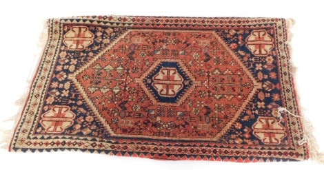 A Persian rug, in blue, red and cream, with a central medallion and four narrow borders, 104cm x 63cm.