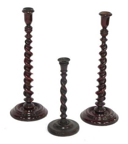 A pair of 19thC stained beech barley twist candle sticks, 51cm high, and a single barley twist oak candlestick, 33cm high. (3)