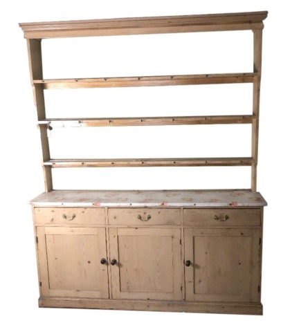 A Victorian stripped pine dresser, with plate rack and three cupboard and three drawer base on plinth, 237cm high, 190cm wide, 43cm deep.