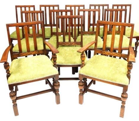 A set of twelve oak dining chairs, inc. two carvers, each with a green padded seats