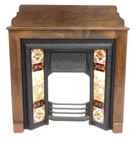 A Victorian style fireplace, with stained pine surround and majolica type tiles to the cast iron inset, 123cm high, 106cm wide, 20cm deep.