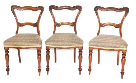 A set of three William IV rosewood balloon back dining chairs, with scroll carved backs, serpentine seats and turned forelegs.