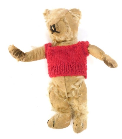 A 20thC plush blonde jointed Teddy Bear, worn, with red jumper, 28cm high.