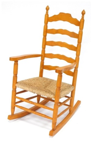 A beech ladder back rocking chair, with rush seat.