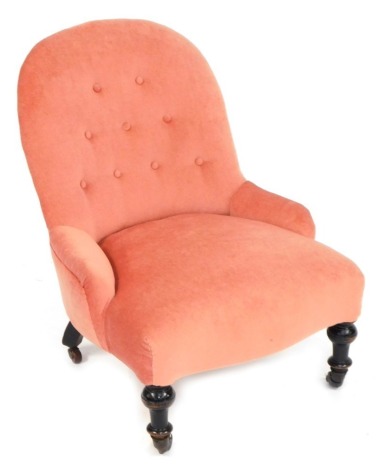 A Victorian nursing chair, with pink buttoned upholstery and ebonised turned legs with castors.