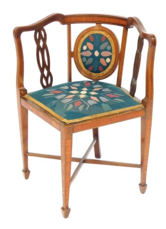 An Edwardian mahogany satinwood cross banded corner chair, with a padded woolwork back, flanked by pierced splats, a padded seat on square tapering legs.