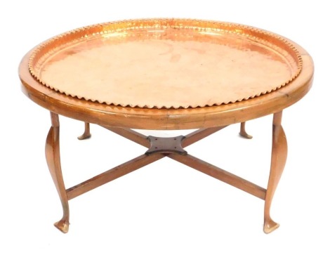 A Continental coffee table, the circular top inset with a hammered copper tray, on shaped supports, 95cm wide.