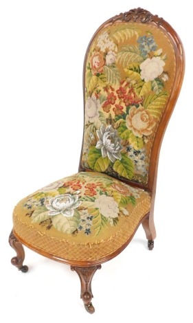 A Victorian walnut spoon back nursing chair, the padded back and seat decorated with wool work and bead work flowers and leaves, on carved cabriole legs with castors.