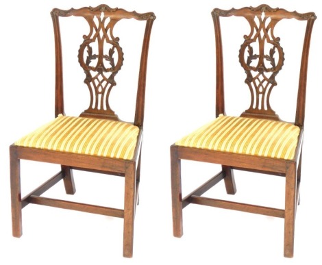 A pair of George III mahogany dining chairs, each with a carved pierced splat, drop in seat, on chamfered legs with H stretcher, (AF).