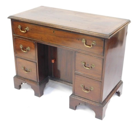 An early 20thC mahogany kneehole desk, in mid 18thC style, the cross banded top with a moulded edge above one long and four short drawers, each with brass handles, flanking cupboard on bracket feet, 75cm high, 96cm wide, 48cm deep.