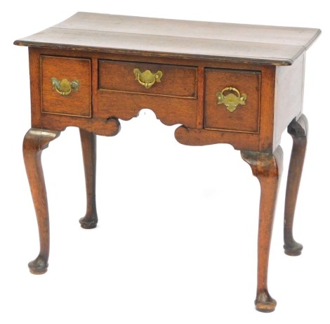 A late 18thC oak lowboy, the rectangular top with a moulded edge, above three drawers each with shaped and engraved brass drop handles and a shaped apron, on cabriole legs with pad feet, 78cm wide.