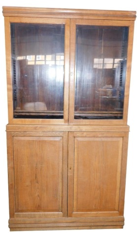 An oak part glazed cabinet bookcase, with fielded panel two door base, 222cm high, 123cm wide.