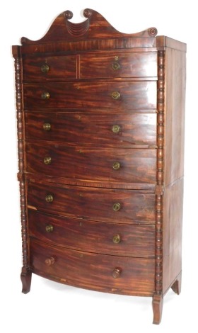 A William IV mahogany bow front tallboy or chest on chest, with scroll pediment, bobbin turned uprights, graduated drawers with brass handles, 203cm high, 119cm wide.