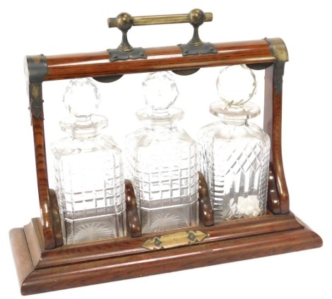 A 19thC tantalus, on oak and brass bound supports, with three matched decanters, 33cm high, 40cm wide, 18cm deep. (AF)