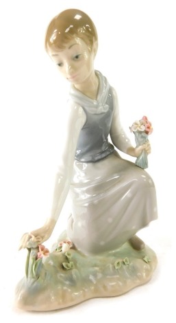 A Lladro figure of a lady picking flowers, 21cm high.