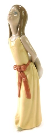 A Lladro figure of a female in yellow dress with hat, in thoughtful pose, 24cm high.