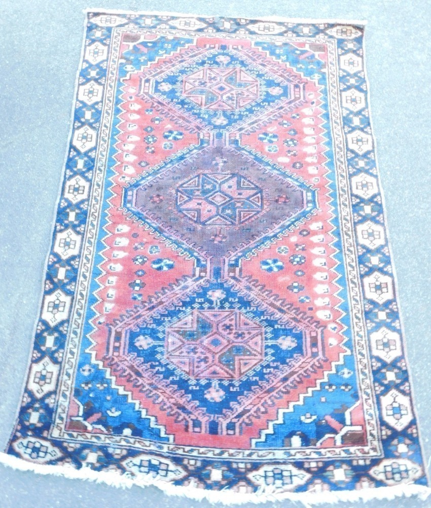 A Shiraz rug, red ground decorated with three joining central