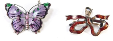 Two silver and enamel brooches, comprising a bow design red enamel brooch, 3.5cm wide, and a purple and green enamel silver butterfly brooch, 4cm wide. (2)