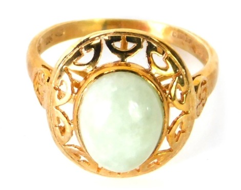 A 9ct gold jade dress ring, with cabouchon cut oval light jade stone, pierced design border, with V splayed shoulders, size N, 2.7g all in.