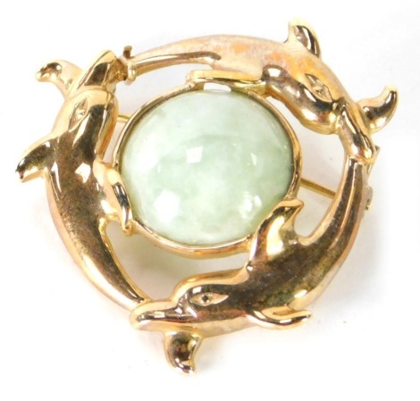 A jade brooch, with outer row of three dolphins and light green jadite centre, in yellow metal frame, unmarked, believed to be 9ct, 3cm wide, 7.8g all in.