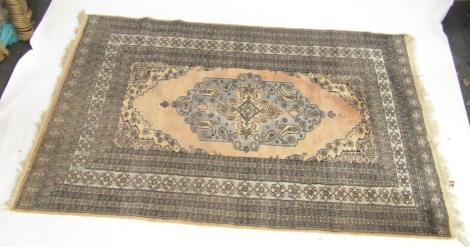 A Turkish rug, peach ground decorated with a central medallion with floral and foliate motifs, against a turquoise ground, within repeating floral borders, 216cm x 135cm.