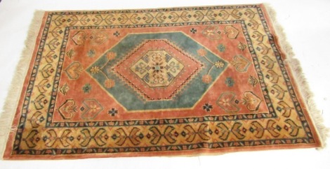 A Turkish rug, pink ground decorated with a central medallion with floral motifs, within repeating floral borders, 175cm x 122cm.