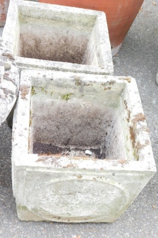 A pair of concrete planters, of square form, decorated to the sides with galleons within roundels, 54cm high, 36cm wide.