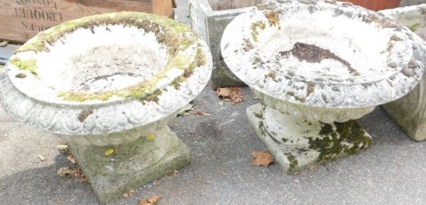 A pair of reconstituted stone circular planters, of fluted form, raised on a square pedestal, 38cm high, 57cm diameter.