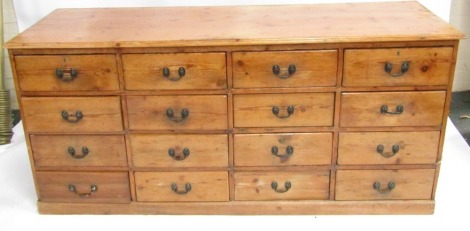 A 19thC Victorian stripped pine chest of 16 drawers with iron loop handles, 85cm high, 186cm wide, 65cm deep.