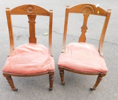 Two Victorian oak framed lounge chairs, each with a pink upholstered seat and carved daisy back. (2)