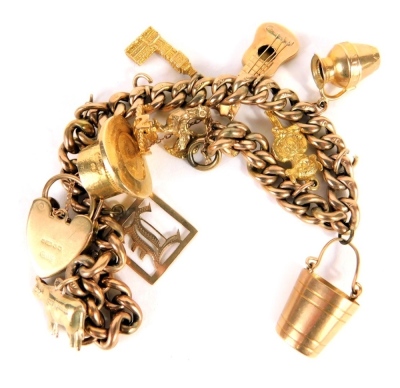 A 9ct gold charm bracelet, with curb links and heart shaped padlock clasp, with a number of various charms to include bucket, Lincoln Imp, 2cm high, etc., some yellow metal, some marked 9c, etc., 26g all in.