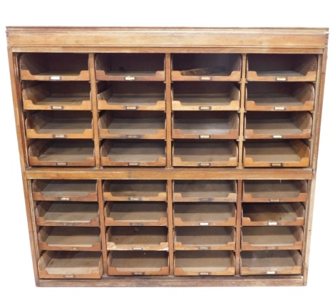 A selection of early 20thC oak shop fitting, with a collection of sliding trays, each with part gilt metal naming plates, lacking doors, incomplete (AF), 142cm high, 153 wide.