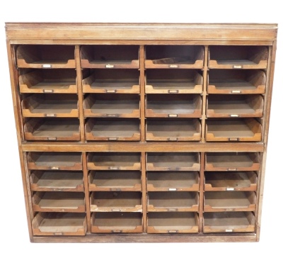 A selection of early 20thC oak shop fitting, with a collection of sliding trays, each with part gilt metal naming plates, lacking doors, incomplete (AF), 142cm high, 153 wide.