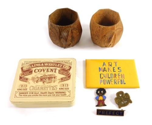 Two Robert Thompson of Kilburn design Mouseman napkin rings, 6cm high (2), and a tin containing three enamel badges. (a quantity)