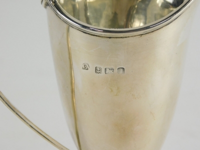 A George V helmet shaped cream jug, with strap work handle on square foot, Birmingham 1910, 13cm high, 2.5oz. - 2