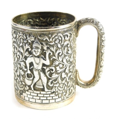 A 20thC Indian mug, heavily repousse decorated with figures and scrolls, with a C scroll handle, and plain circular foot, white metal, unmarked. 9cm high.