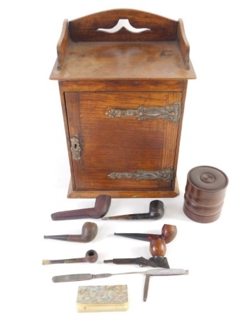 An Edwardian oak smokers cabinet, with three part galleried top, hinged front revealing part fitted interior, with tobacco bar and associated pipes, with elaborate copper hinges, 39cm high, 27cm wide, 23cm deep.