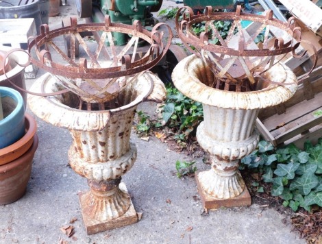 A pair of Victorian cast iron urns, each of circular form with bellied bodies, on square feet, 56cm high, and two iron hanging planters. (4, AF)