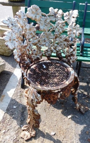 A cast iron seat, of naturalistic form, the back set with leaves and berries, on a mesh work seat terminating in triple scroll legs, 80cm high.