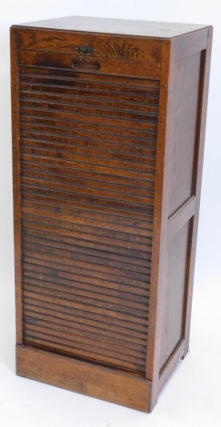 A mid 20thC oak filing cabinet, with a tambour door enclosing sliding trays, each with metal plaques on a plinth, 107cm high, 45cm wide.