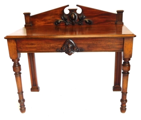 A Victorian mahogany hall or serving table, the raised back with a broken pediment and stylised leaf and oval crest, the base with a canted edge above a frieze carved with a shell, scrolls, etc., on turned legs, 117cm wide.