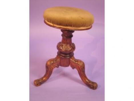 A Victorian walnut adjustable piano stool on a turned and leaf carved column