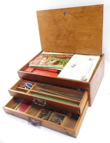 A Meccano set, in two drawer oak cabinet, to include wheels, screws and bars, in red and green. (a quantity)