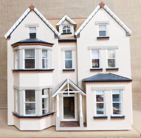 A three storey Victorian style doll's house, with turreted top and chimney, with bay windows, in a pink finish, 75cm high, 50cm deep, 72cm wide.