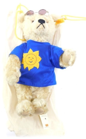 A Steiff mohair Teddy Bear, in a blue t-shirt with sun face, with sun hat and sunglasses, with carry bag.