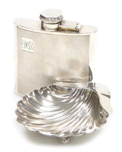 An Edwardian VII silver butter dish, of scallop shell form, raised on three ball feet, Chester 1906, 1.75oz, 9.5cm wide, and a silver plated hip flask, with engine turned decoration and initialled cartouche, 11cm high.