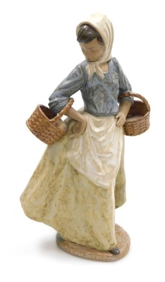 A Nao matte porcelain figure of a young girl holding baskets, printed and impressed marks, 36cm high.